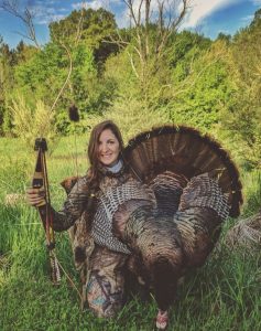 Bowhunter with turkey taken using traditional archery equipment