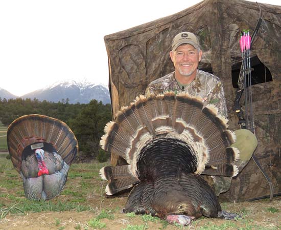 Fred Eichler poses with a turkey he took using his traditional bow, as well as a blind and turkey decoy.